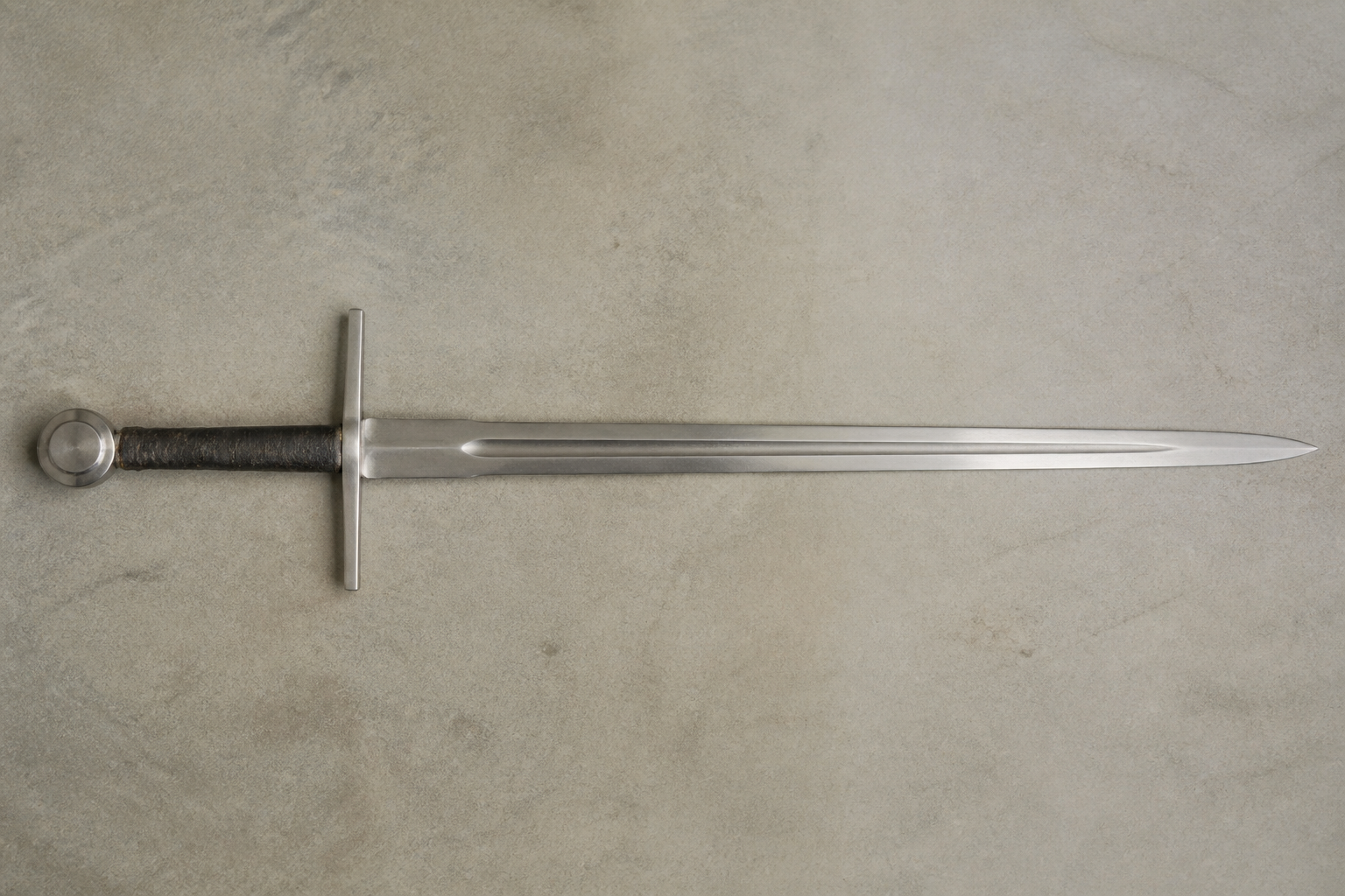 A double edged sword laid flat on a plain surface with every part visible from hilt to tip: pommel, wrapped grip, straight cross guard, ricasso, fuller running down the blade, edges and point